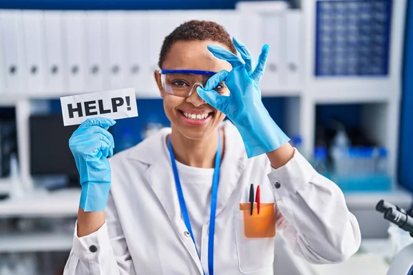美しいアフリカ系アメリカ人の女性は 科学者の研究室で働いている指を通して見て目に手でOkサインをすることで笑顔を助ける — ストック写真