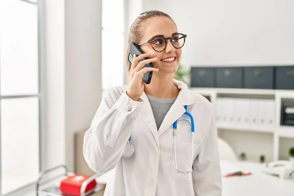 Młoda Blondynka Mundurze Lekarskim Rozmawiająca Przez Smartfona Pracującego Klinice — Zdjęcie stockowe