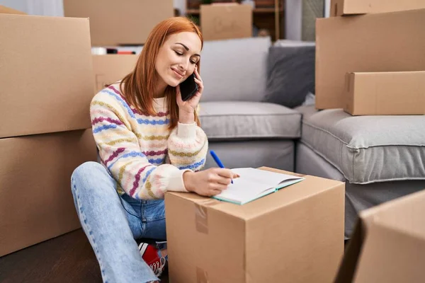 Jonge Kaukasische Vrouw Praten Smartphone Schrijven Notebook Nieuw Huis — Stockfoto