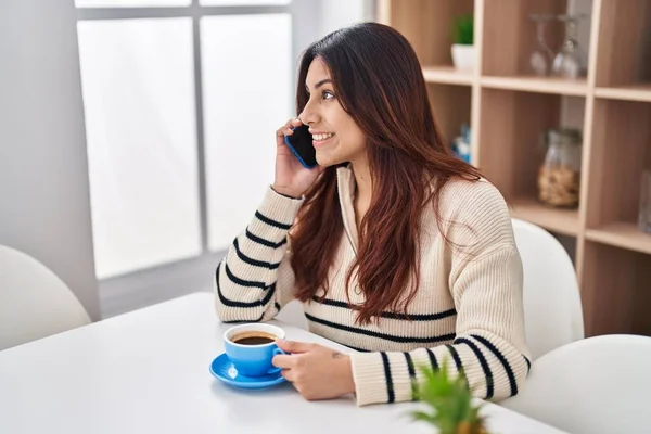Young Hispanic Woman Drinking Coffee Talking Smartphone Home — Zdjęcie stockowe