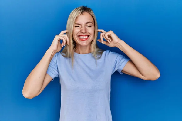 Mooie Blonde Vrouw Draagt Casual Shirt Blauwe Achtergrond Bedekt Oren — Stockfoto