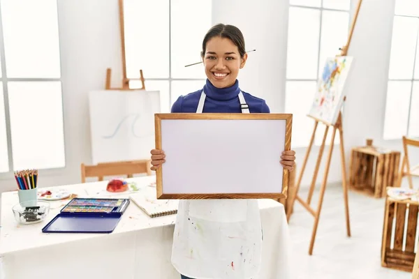 年轻的拉丁女子带着自信的笑容在艺术工作室拿着白板 — 图库照片