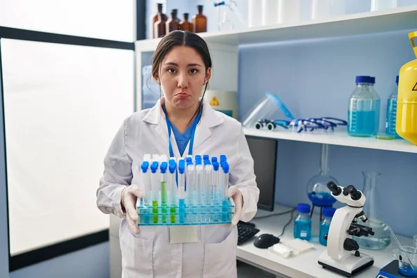 Young latin woman working at scientist laboratory depressed and worry for distress, crying angry and afraid. sad expression.