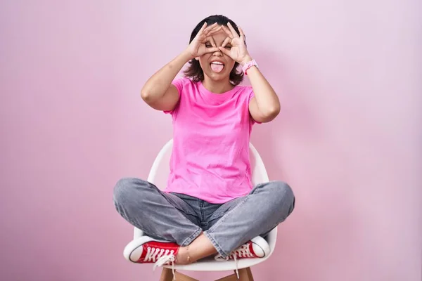 Латиноамериканская Молодая Женщина Сидящая Стуле Розовом Фоне Делает Нормальный Жест — стоковое фото