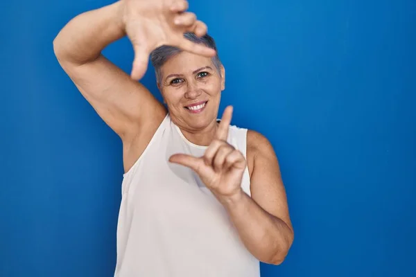 Orta Yaşlı Beyaz Kadın Mavi Arka Planda Durup Gülümsüyor Elleri — Stok fotoğraf