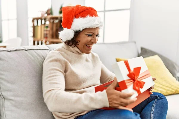 Middle Age Hispanic Woman Unboxing Gift Sitting Sofa Christmas Tree — Stock Photo, Image