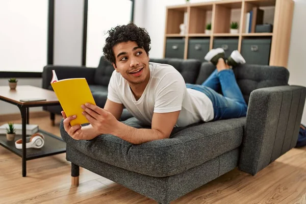 Jovem Hispânico Homem Lendo Livro Deitado Sofá Casa — Fotografia de Stock