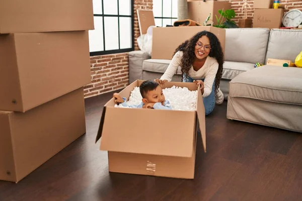 Mother and son playing with cardboard as a car at new home