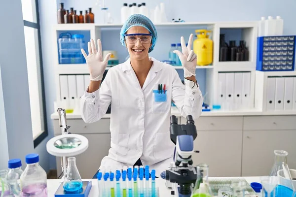 Brunette Woman Working Scientist Laboratory Showing Pointing Fingers Number Eight — Stock Photo, Image