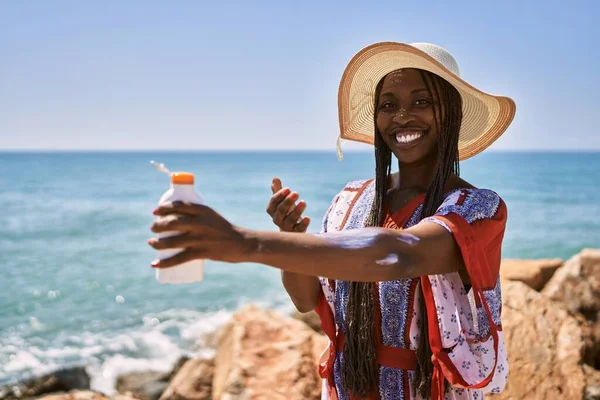 Νεαρή Αφροαμερικανή Γυναίκα Χαμογελά Ευτυχισμένη Χρησιμοποιώντας Αντηλιακή Λοσιόν Στην Παραλία — Φωτογραφία Αρχείου
