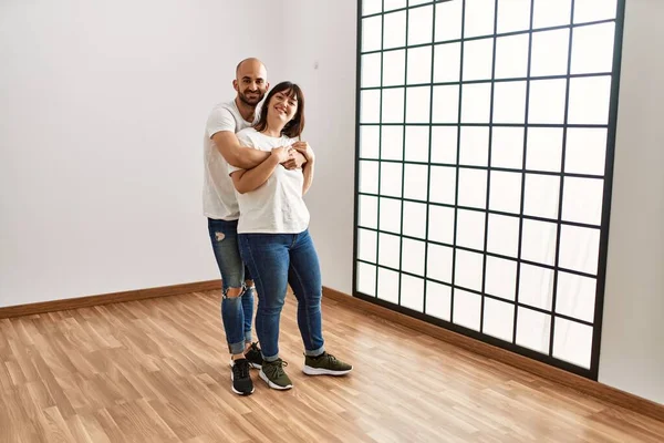 Jovem Casal Hispânico Sorrindo Feliz Abraçando Casa Nova Vazia — Fotografia de Stock