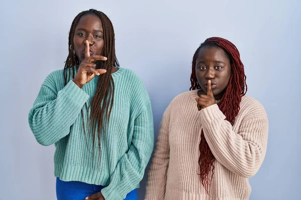 Две Африканки Стоящие Синем Фоне Просят Тишины Пальцем Губах Молчание — стоковое фото