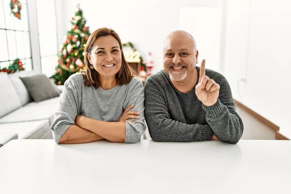 Middle Age Hispanic Couple Sitting Table Christmas Tree Showing Pointing — 图库照片
