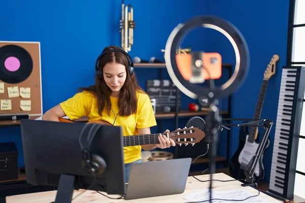 Young woman musician having online classical guitar class at music studio