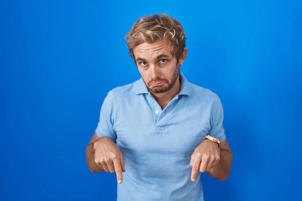 Caucasian Man Standing Blue Background Pointing Looking Sad Upset Indicating — Zdjęcie stockowe