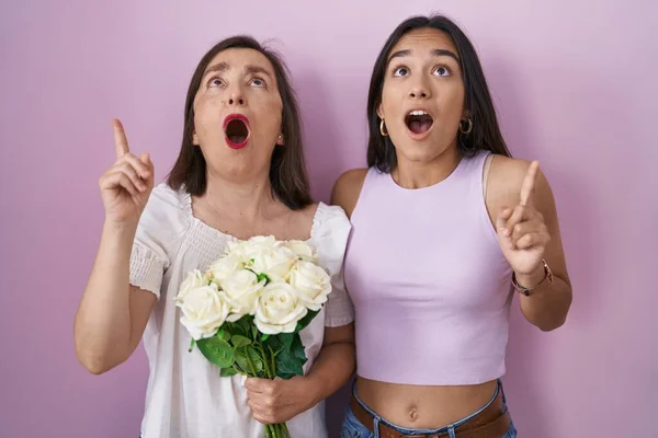 Mãe Hispânica Filha Segurando Buquê Flores Brancas Espantadas Surpresas Olhando — Fotografia de Stock