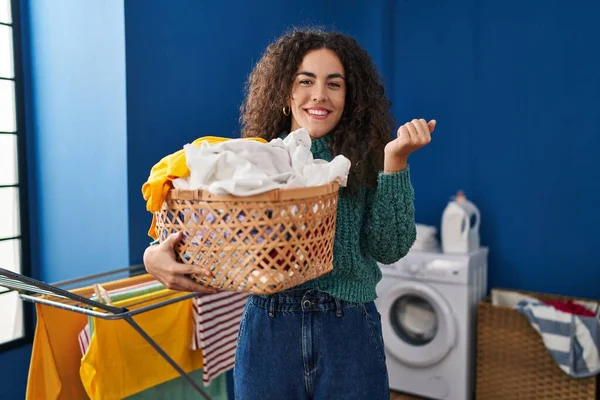 Young Hispanic Woman Holding Laundry Basket Screaming Proud Celebrating Victory — Stockfoto
