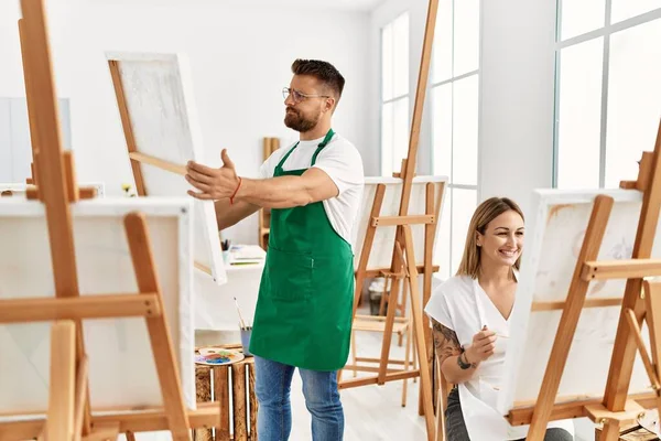 若い白人のカップルは アートスタジオで幸せな絵を笑っています 立ってキャンバスを持っている男 — ストック写真