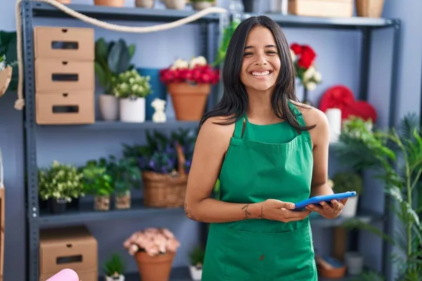 Brunette woman working at florist shop holding tablet smiling and laughing hard out loud because funny crazy joke.