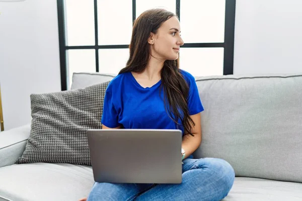 年轻的黑发女人在家里用笔记本电脑看一边 带着自信的微笑放松自己的姿态 — 图库照片