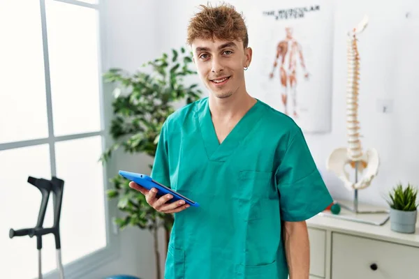 Young Caucasian Physio Man Using Touchpad Clinic Looking Positive Happy — Stok fotoğraf