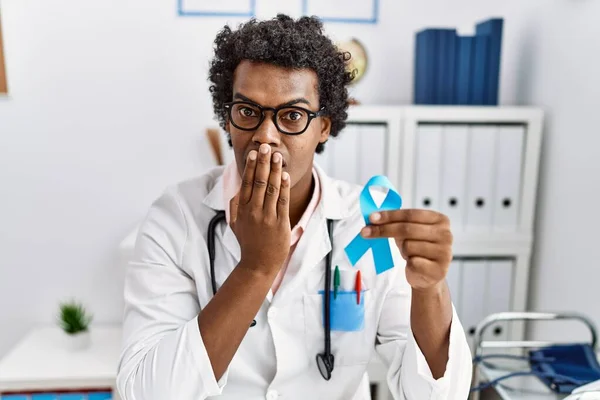 Médico Africano Sosteniendo Cinta Azul Cubriendo Boca Con Mano Sorprendido —  Fotos de Stock