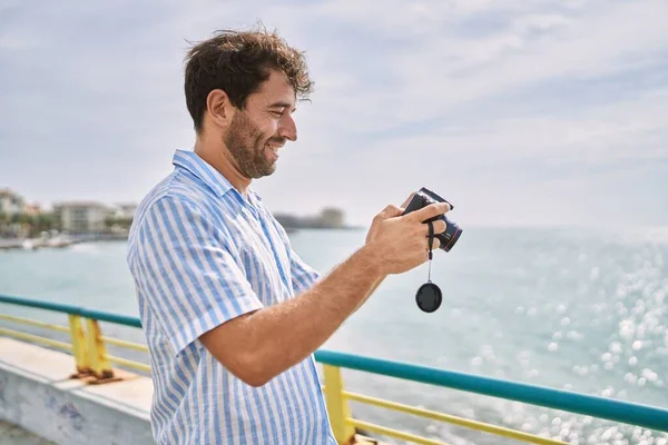 Młody Latynos Uśmiecha Się Szczęśliwy Używając Kamery Plaży — Zdjęcie stockowe