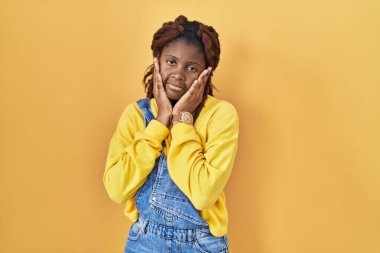 African woman standing over yellow background tired hands covering face, depression and sadness, upset and irritated for problem 