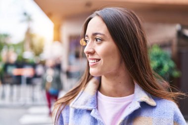 Young beautiful hispanic woman smiling confident looking to the side at street