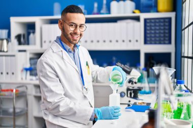 African american man scientist pouring liquid on bottle at laboratory