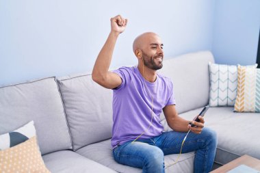 Young bald man listening to music and dancing at home