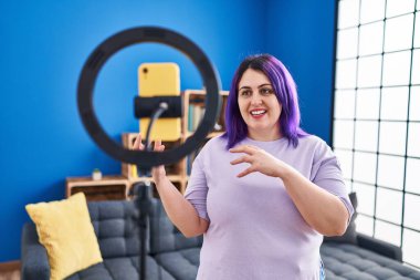 Young beautiful plus size woman having video call standing at home