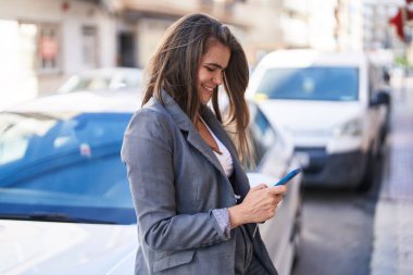 Sokakta akıllı telefon kullanan kendine güvenen genç bir kadın.