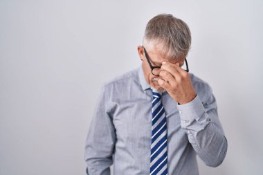 Gri saçlı, gözlüklü, burnu ve gözleri ovuşturmaktan yorgun, yorgun ve başı ağrıyan İspanyol iş adamı. Stres ve hüsran kavramı. 