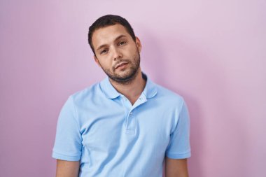 İspanyol adam pembe arka planda duruyor. Uykulu ve yorgun görünüyor. Yorgun ve akşamdan kalma.. 