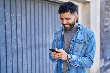 Sokakta akıllı telefon kullanan, kendine güvenen genç bir İspanyol.