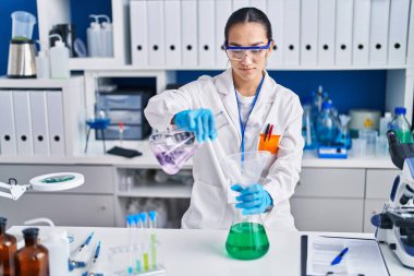 Laboratuvarda sıvıyı ölçen genç İspanyol bilim kadını.