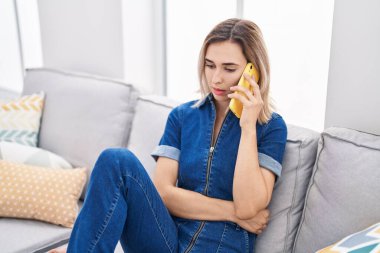 Evde akıllı telefondan konuşan genç bir kadın.