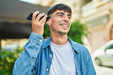 Genç İspanyol adam gülümsüyor. Caddedeki akıllı telefondan kendine güvenen bir sesli mesaj dinliyor.