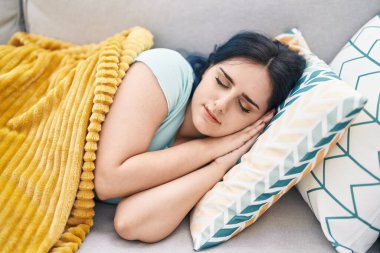 Beyaz bir kadın kanepede uzanıyor ve evinde uyuyor.