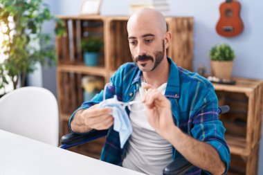 Genç İspanyol adam evde tekerlekli sandalyede oturmuş cam temizliyor.