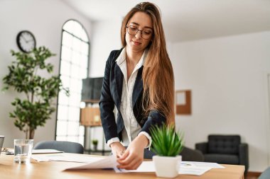 Genç İspanyol iş kadını büroda evrak işleriyle uğraşıyor.