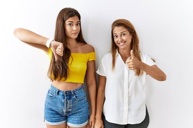 Anne ve kızı birlikte soyutlanmış bir arka planda baş parmaklarını yukarı aşağı hareket ettiriyorlar, anlaşmazlık ve uzlaşma ifadesi. çılgın çatışma 