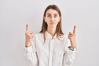 Kafkasyalı genç bir kadın izole edilmiş arka planda dikiliyor üzgün ve üzgün görünüyor, parmaklarıyla yönü gösteriyor, mutsuz ve depresif.. 