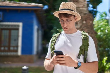Young caucasian man tourist using smartphone at park