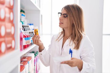 Young woman pharmacist holding pills bottle and prescription at pharmacy