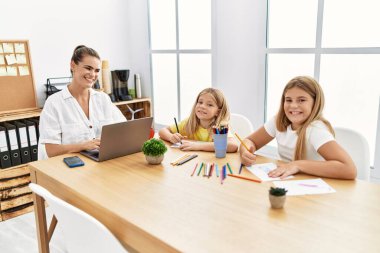 Mother and daughters smiling confident working and drawing at office