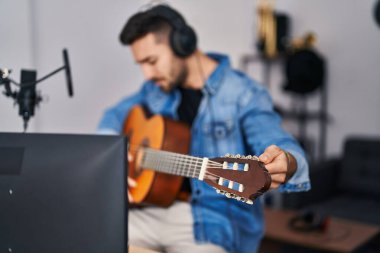 Genç İspanyol adam müzik stüdyosunda klasik gitar çalıyor.