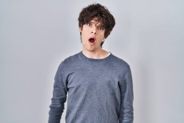 Şok olmuş yüzüyle izole edilmiş arka planda duran genç adam şüpheci ve alaycı görünüyor, ağzı açık bir şekilde şaşırmış. 