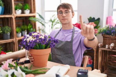 Caucasian blond man working at florist shop pointing with finger up and angry expression, showing no gesture 